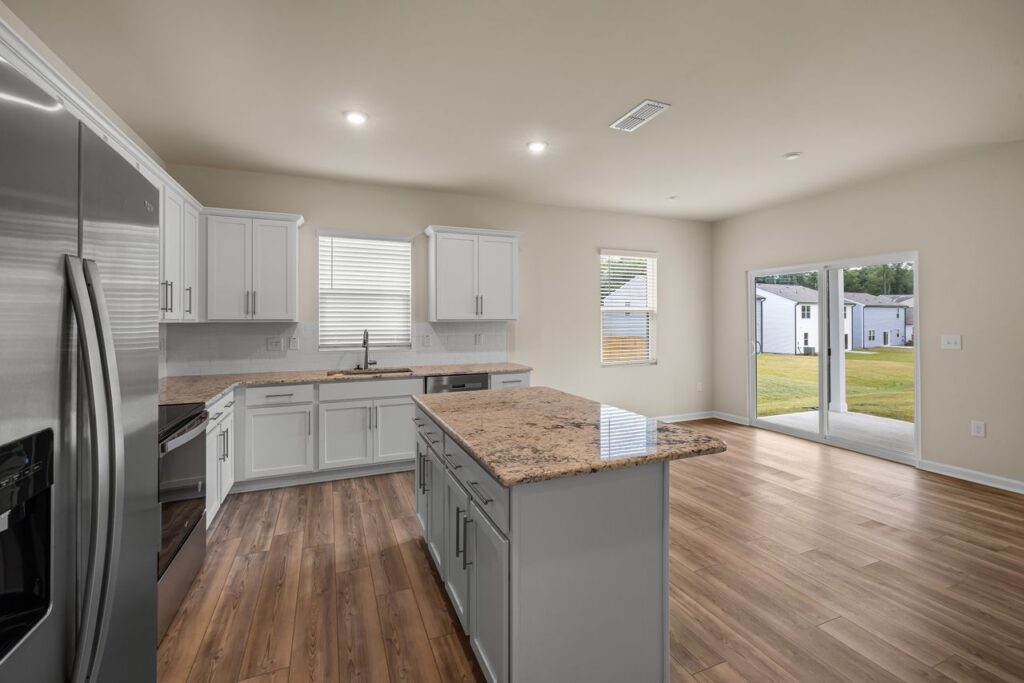 A modern kitchen interior featuring sleek appliances, wooden floors, and ample natural light.