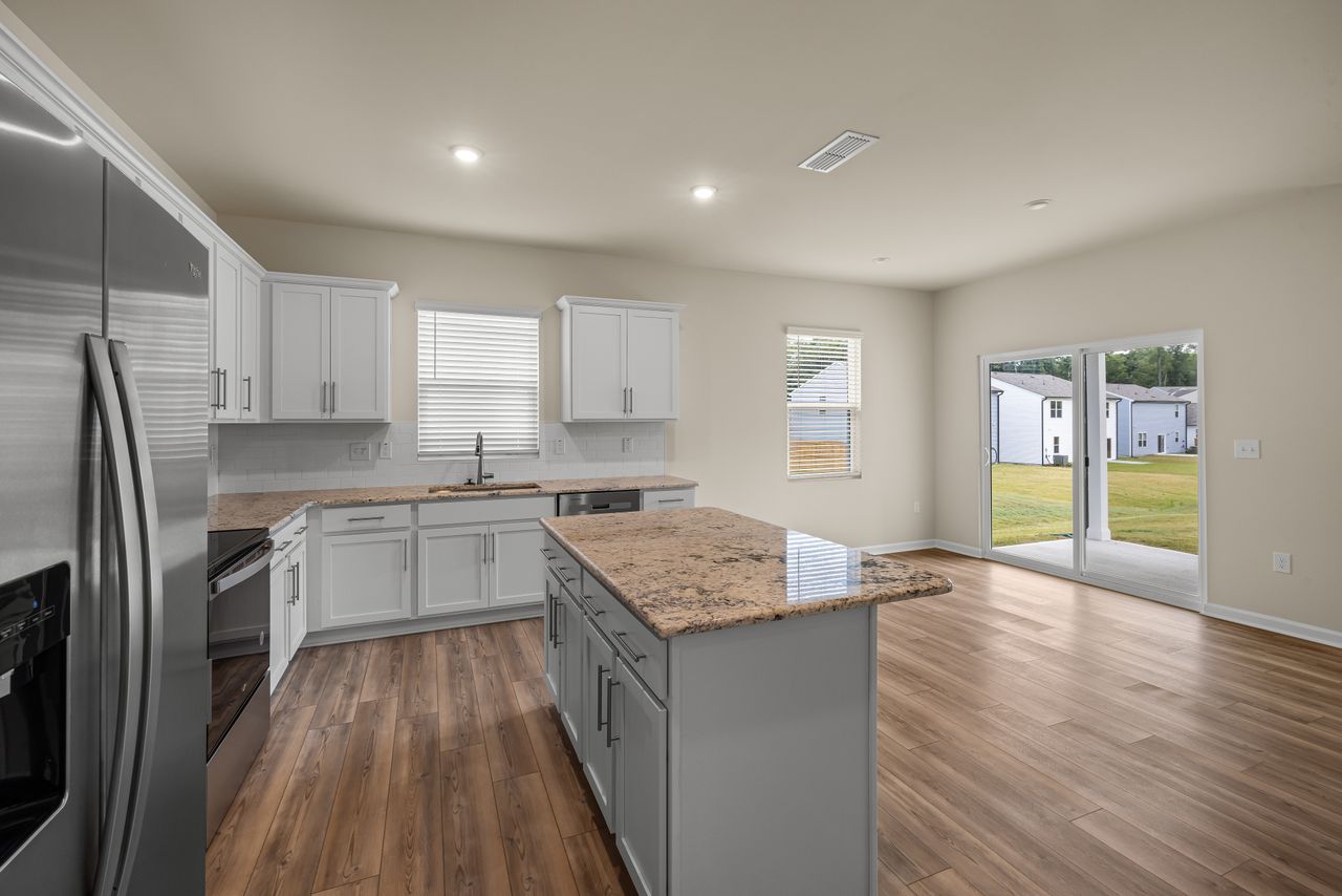 A modern kitchen interior featuring sleek appliances, wooden floors, and ample natural light.